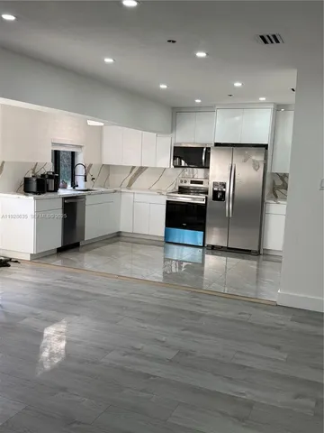 a kitchen with stainless steel appliances kitchen island granite countertop a stove and a refrigerator