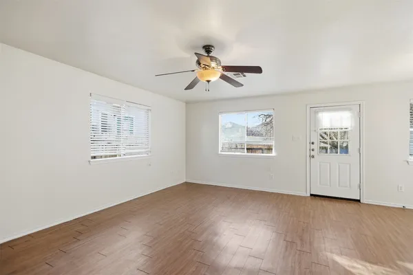 a view of empty room with wooden floor and fan