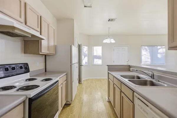 a kitchen that has a sink a stove and a wooden floors