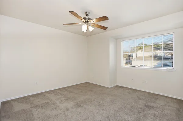 an empty room with a window and a fan