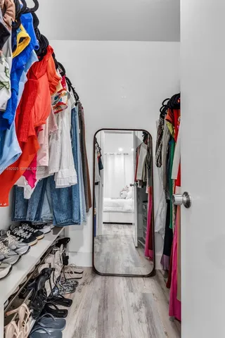 a view of walk in closet with clothes and shoes