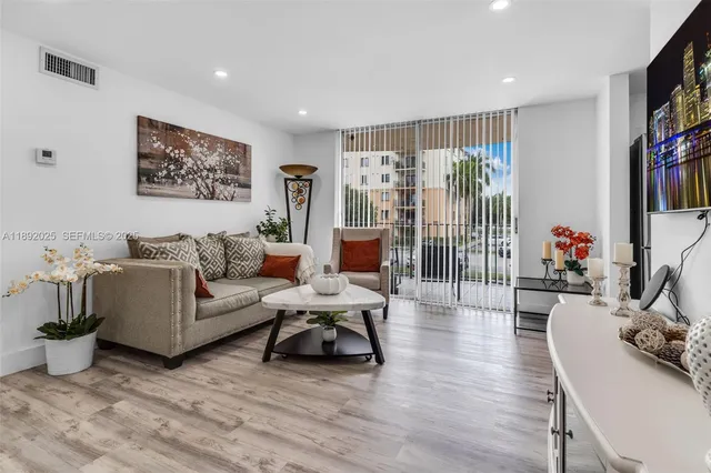 a living room with furniture a flat screen tv and a floor to ceiling window