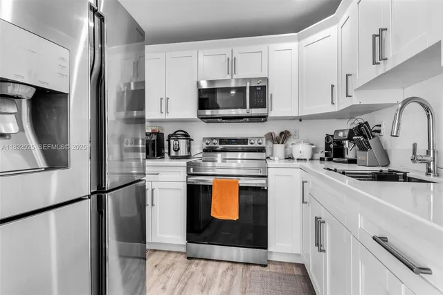 a kitchen with stainless steel appliances granite countertop a refrigerator stove a sink and dishwasher with wooden floor