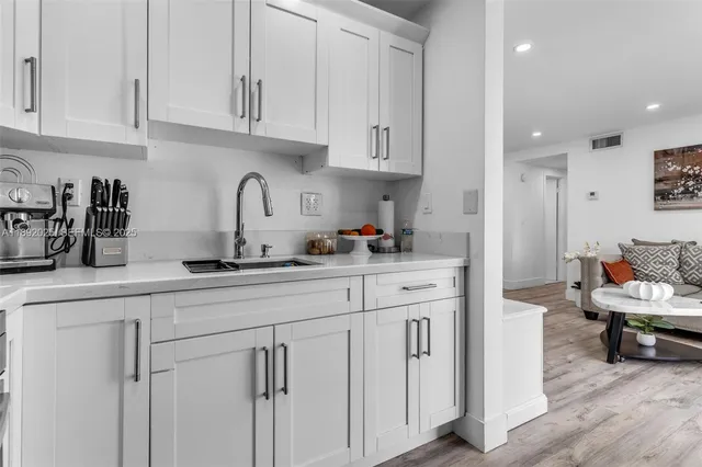 a kitchen with white cabinets and sink
