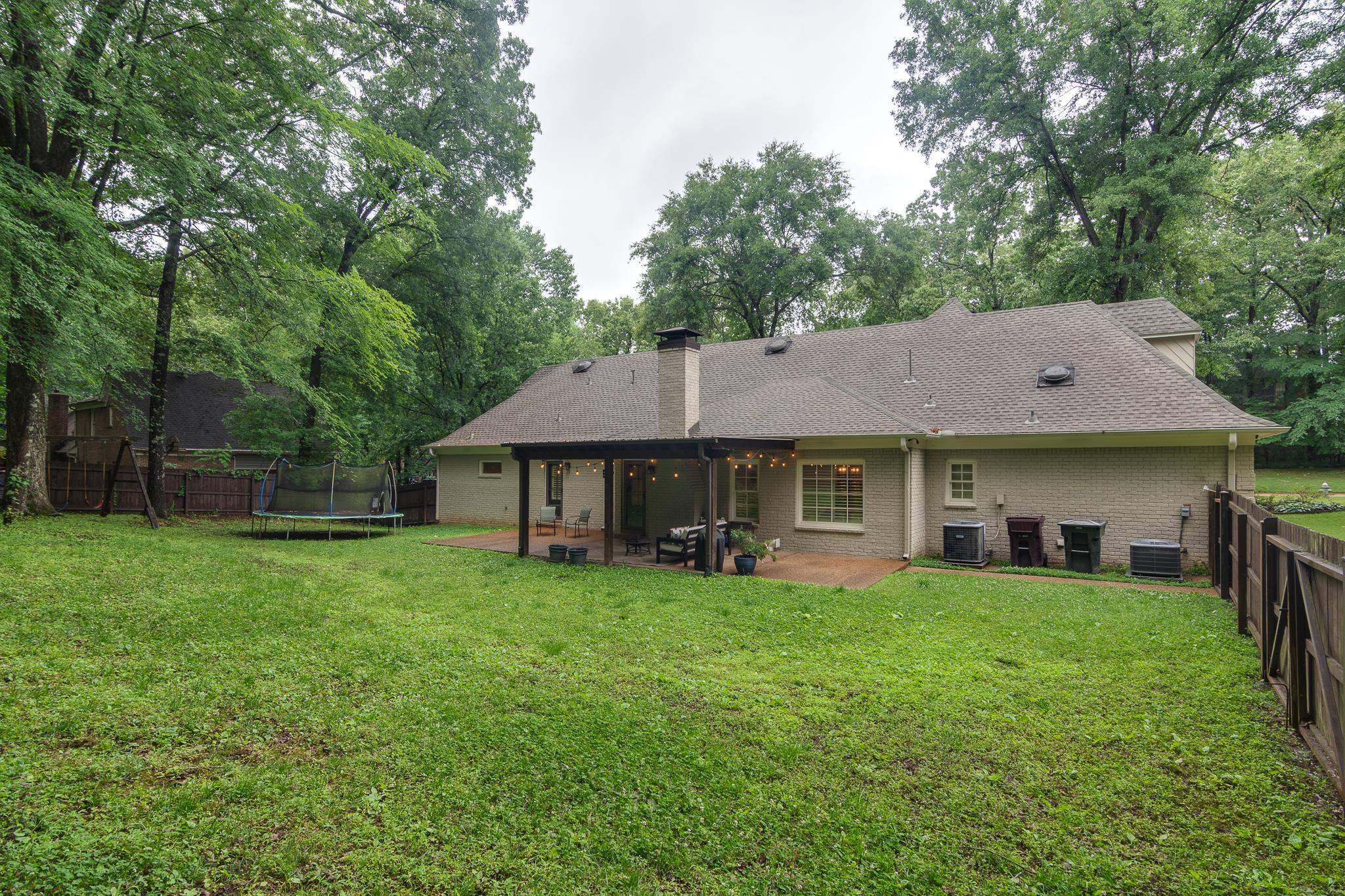 791 North Tree Drive Collierville, TN 38017 - Photo 26 of 27 Expansive rear yard featuring a covered patio, brick exterior, and partial perimeter fencing