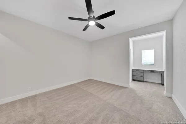 an empty room with windows and fan