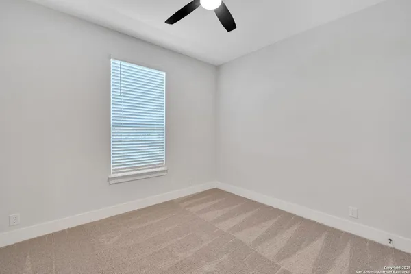 an empty room with a ceiling fan and carpet