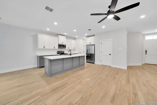 a large kitchen with stainless steel appliances kitchen island a large counter top and wooden floors
