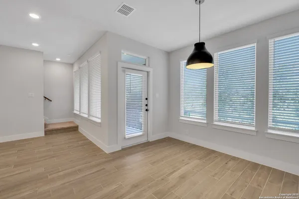a view of an empty room with a window and wooden floor