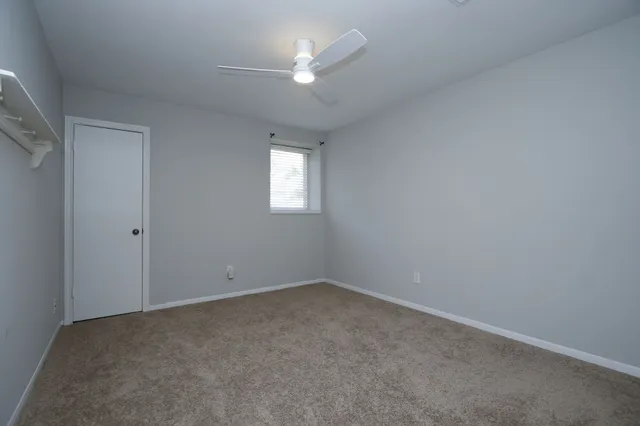 an empty room with a window and a ceiling fan