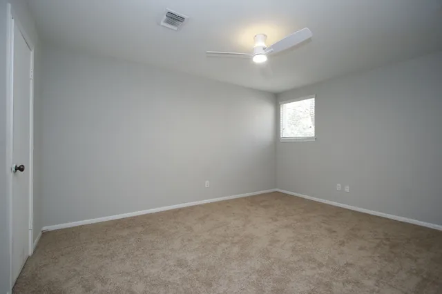 an empty room with a window and a fan