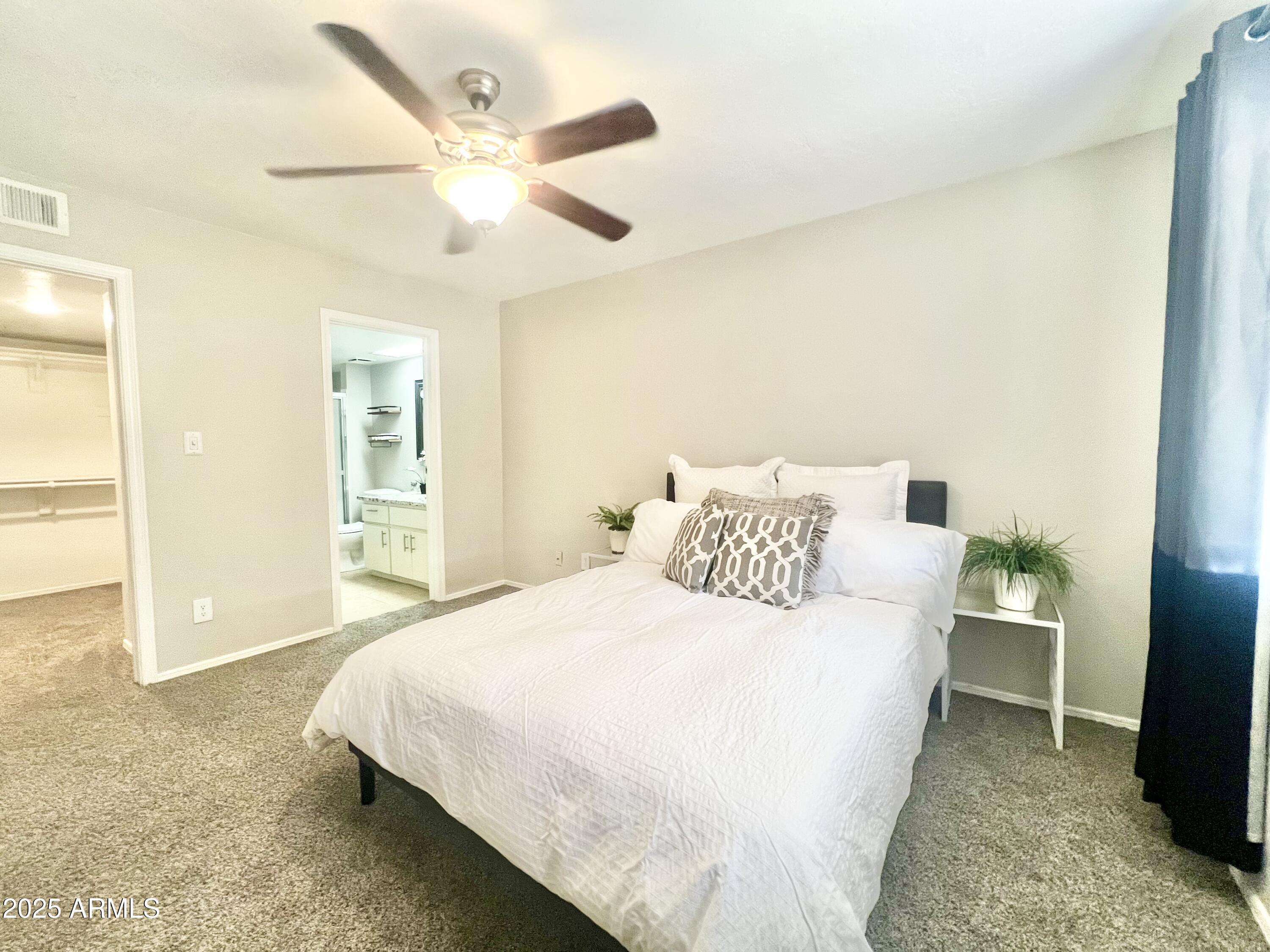 2855 South Ext Road, Unit 220 Mesa, AZ 85210 - Photo 14 of 40 a bedroom with a large bed and a chandelier
