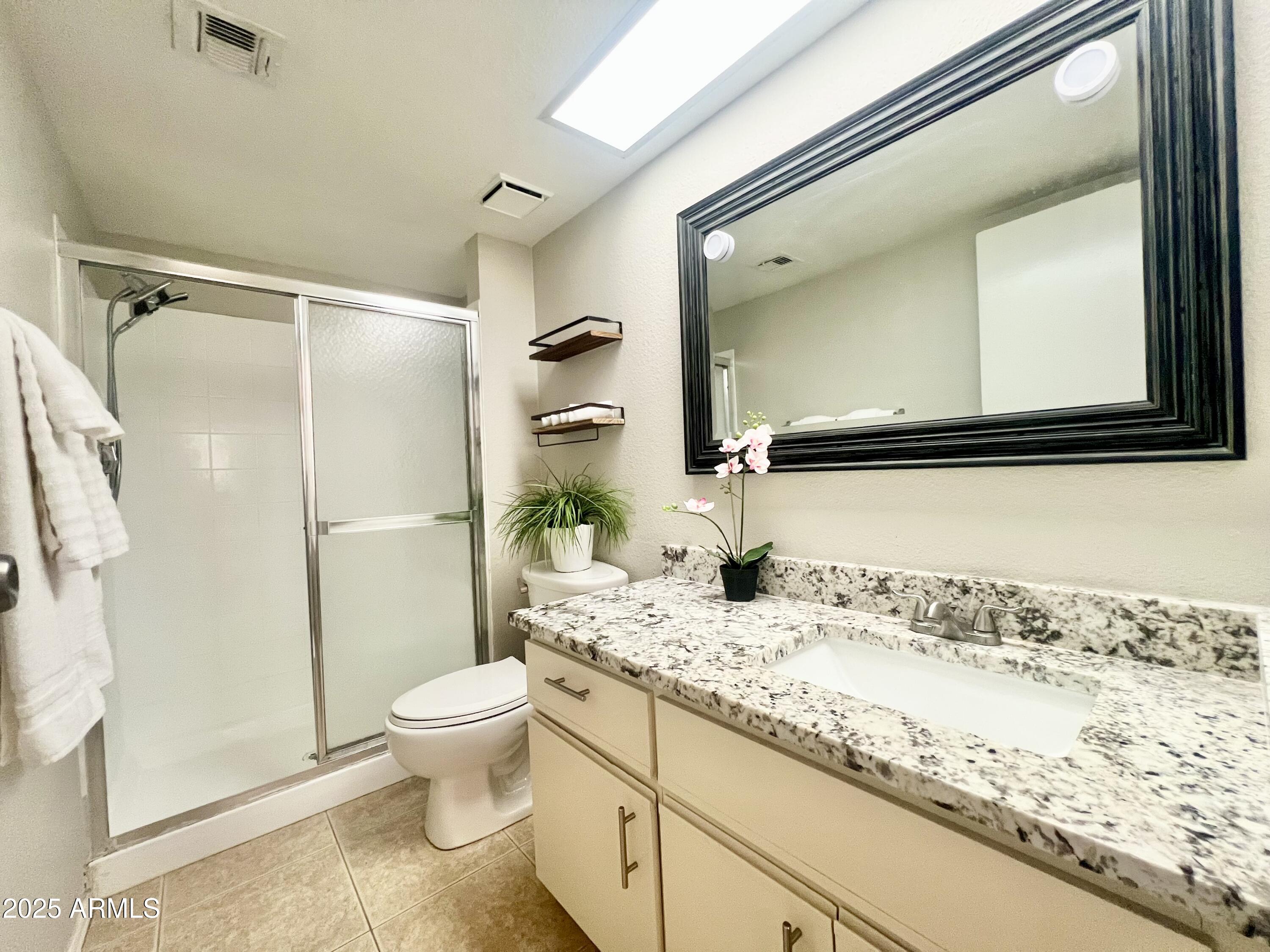 2855 South Ext Road, Unit 220 Mesa, AZ 85210 - Photo 19 of 40 a bathroom with a granite countertop sink mirror vanity and toilet