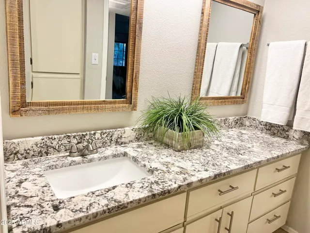 a bathroom with a granite countertop sink and a mirror