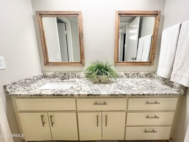 a bathroom with a granite countertop sink and a mirror