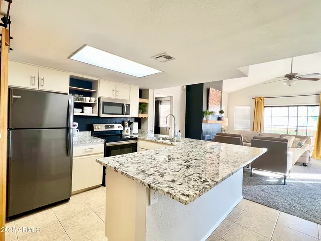 a kitchen with stainless steel appliances granite countertop a refrigerator and a stove top oven