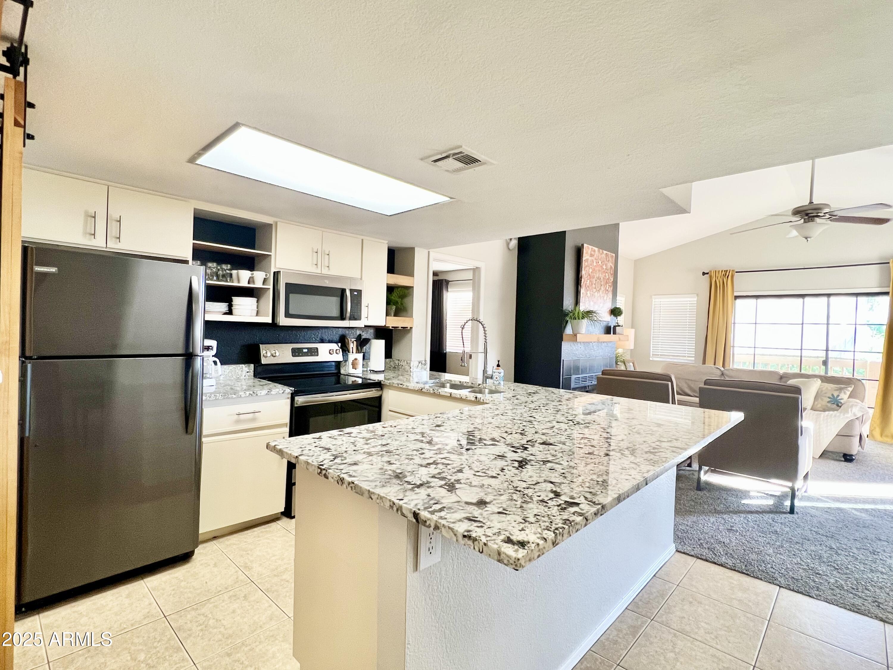 2855 South Ext Road, Unit 220 Mesa, AZ 85210 - Photo 4 of 40 a kitchen with stainless steel appliances granite countertop a refrigerator and a stove top oven