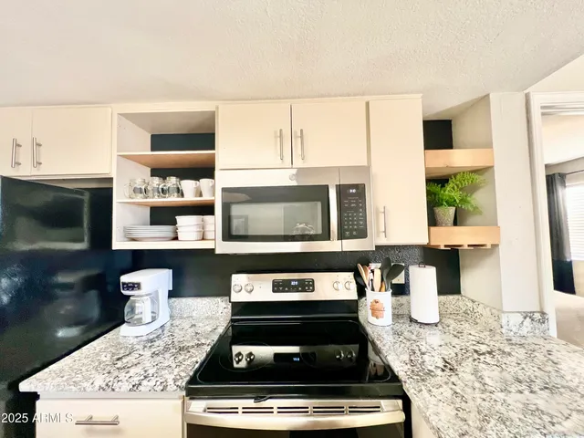 a kitchen with stainless steel appliances granite countertop a stove a sink and a microwave