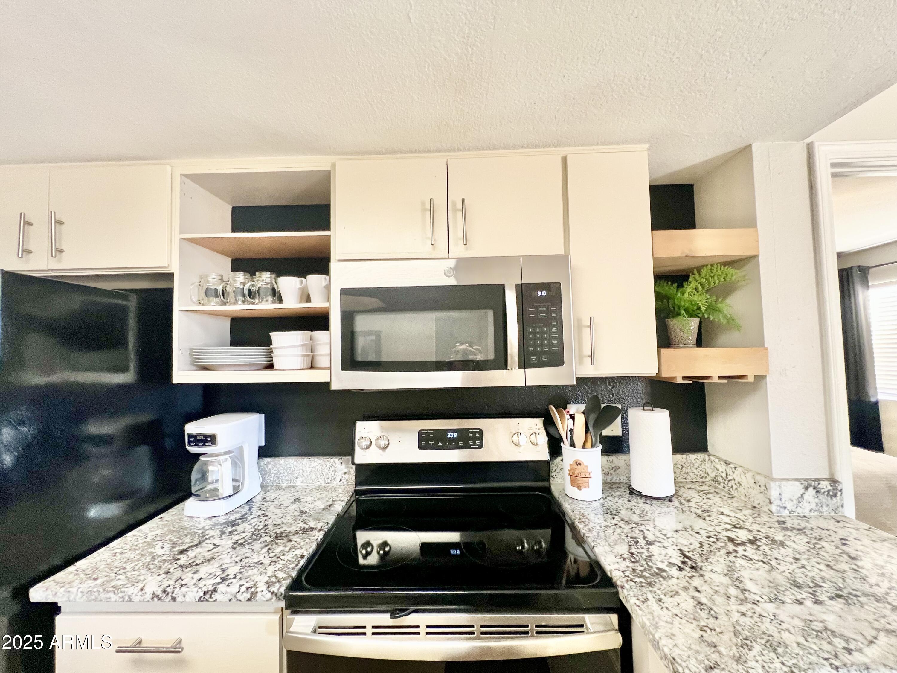 2855 South Ext Road, Unit 220 Mesa, AZ 85210 - Photo 5 of 40 a kitchen with stainless steel appliances granite countertop a stove a sink and a microwave