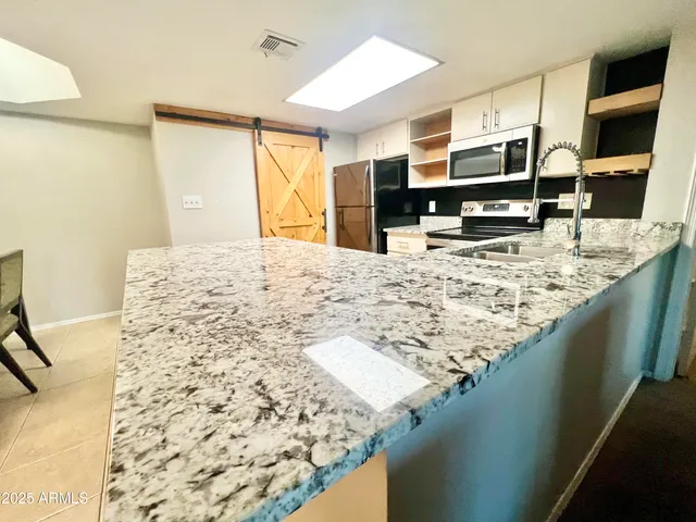 a living room with kitchen island granite countertop furniture and a flat screen tv