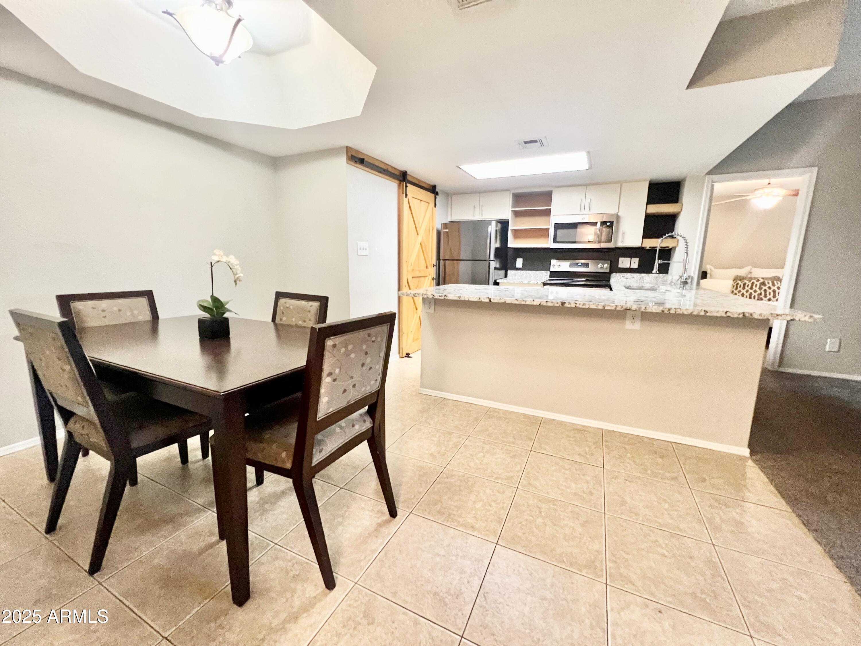 2855 South Ext Road, Unit 220 Mesa, AZ 85210 - Photo 9 of 40 a kitchen with a dining table chairs and refrigerator