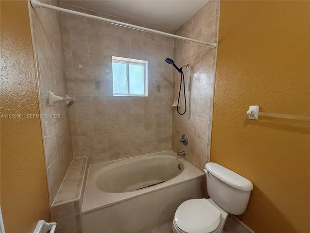 a white toilet sitting next to a bath tub and shower