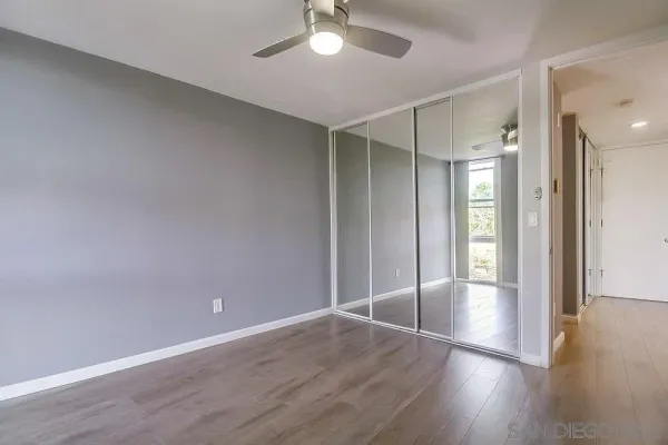 an empty room with wooden floor and a ceiling fan