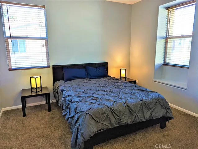 a bedroom with a bed a table and windows