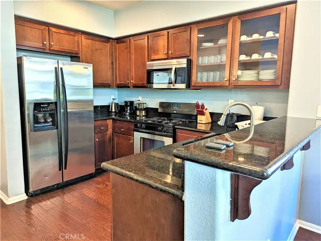 a kitchen with stainless steel appliances granite countertop a refrigerator a stove and a sink with wooden floor