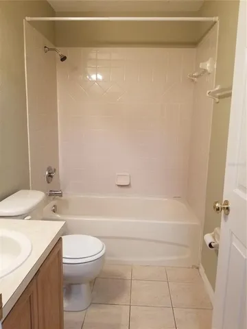 a bathroom with a granite countertop bathtub shower sink vanity and toilet