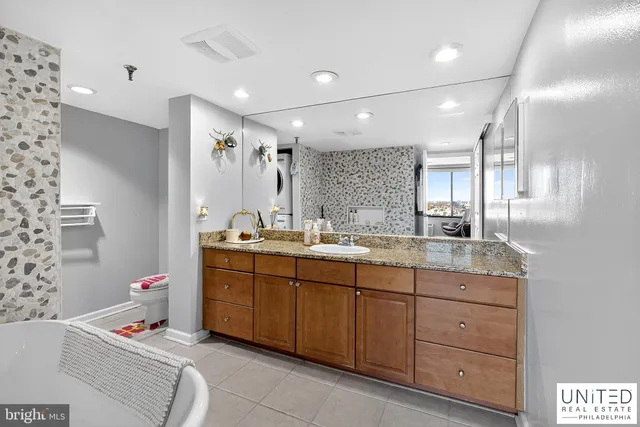 a bathroom with a tub sink double vanity and mirror