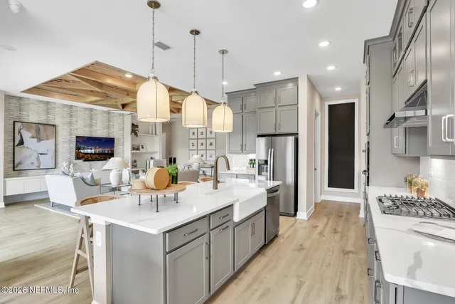 a kitchen with stainless steel appliances kitchen island granite countertop a sink a stove a refrigerator and island with wooden floor