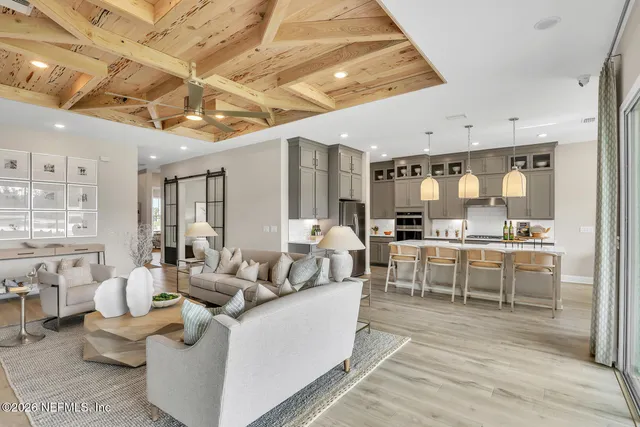 a living room with furniture kitchen view and a large window