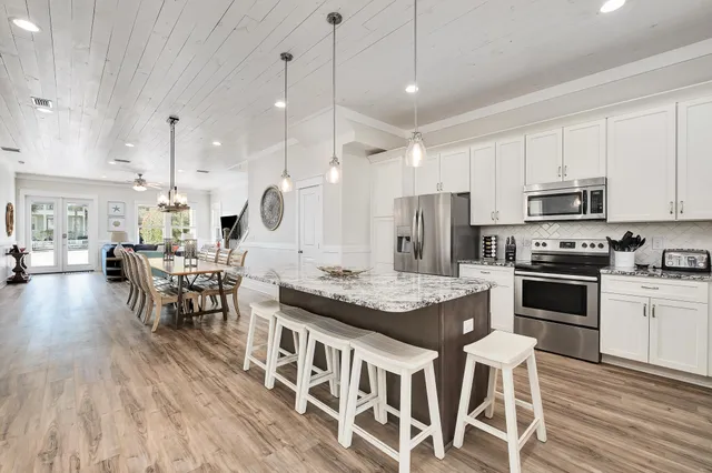 a large kitchen with kitchen island a island a stove a table and chairs in it
