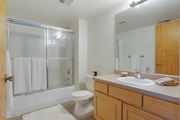 a bathroom with a granite countertop bathtub shower sink vanity and toilet