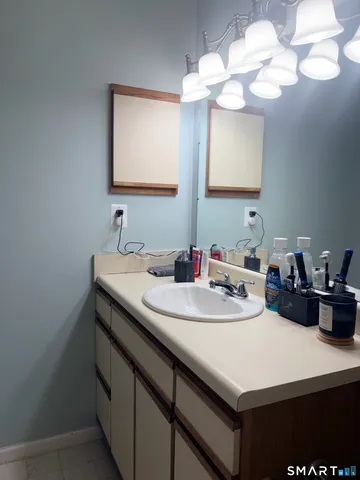 a bathroom with a sink a light fixture and a wall painting