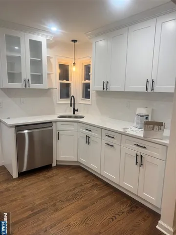 a kitchen with stainless steel appliances granite countertop a sink a stove and white cabinets with wooden floor