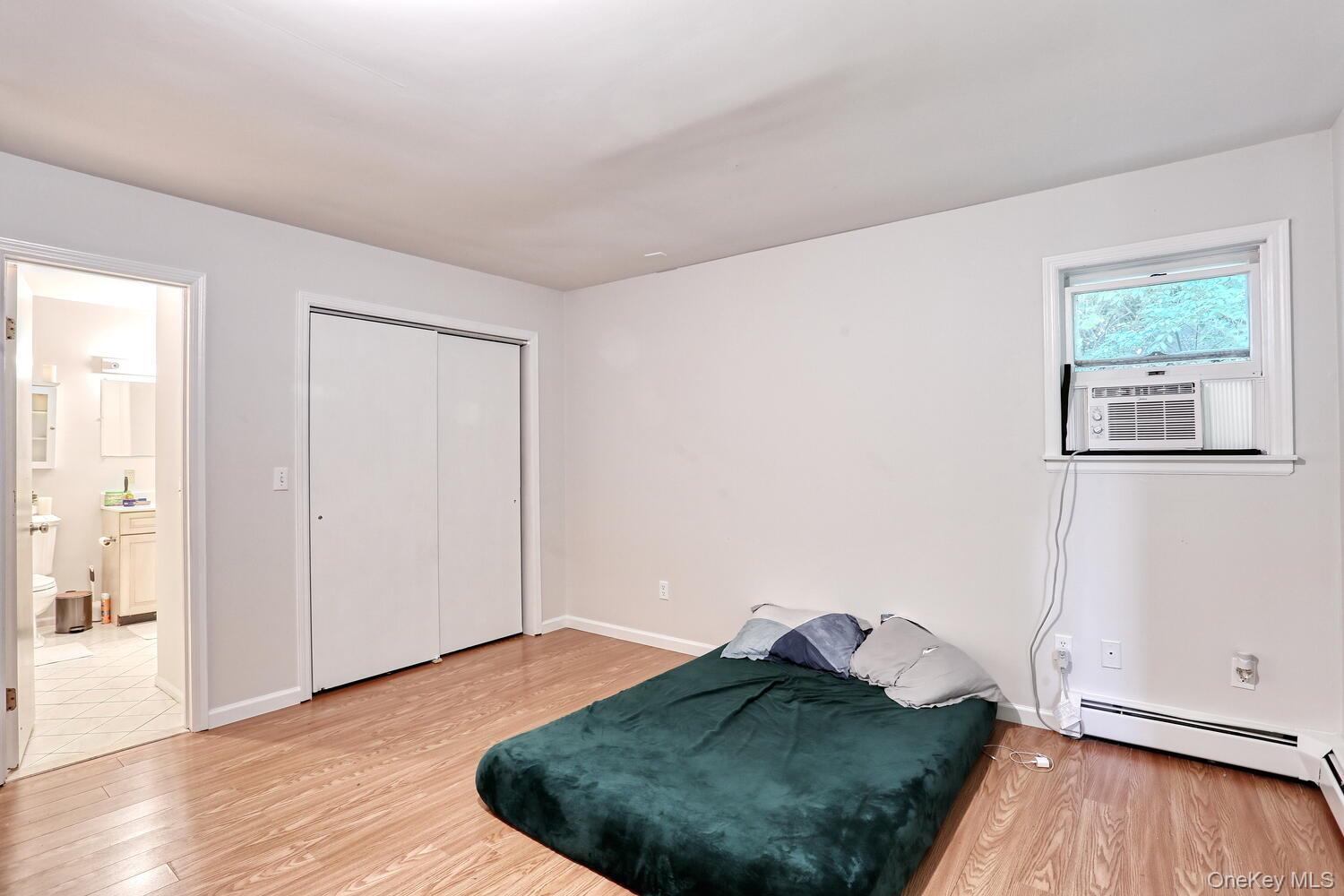 329 Call Hollow Road Haverstraw, NY 10980 - Photo 11 of 28 Bedroom featuring light wood-style floors, ensuite bath, a closet, a baseboard heating unit, and cooling unit