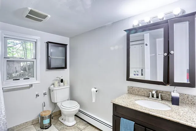 a bathroom with a granite countertop toilet sink and mirror
