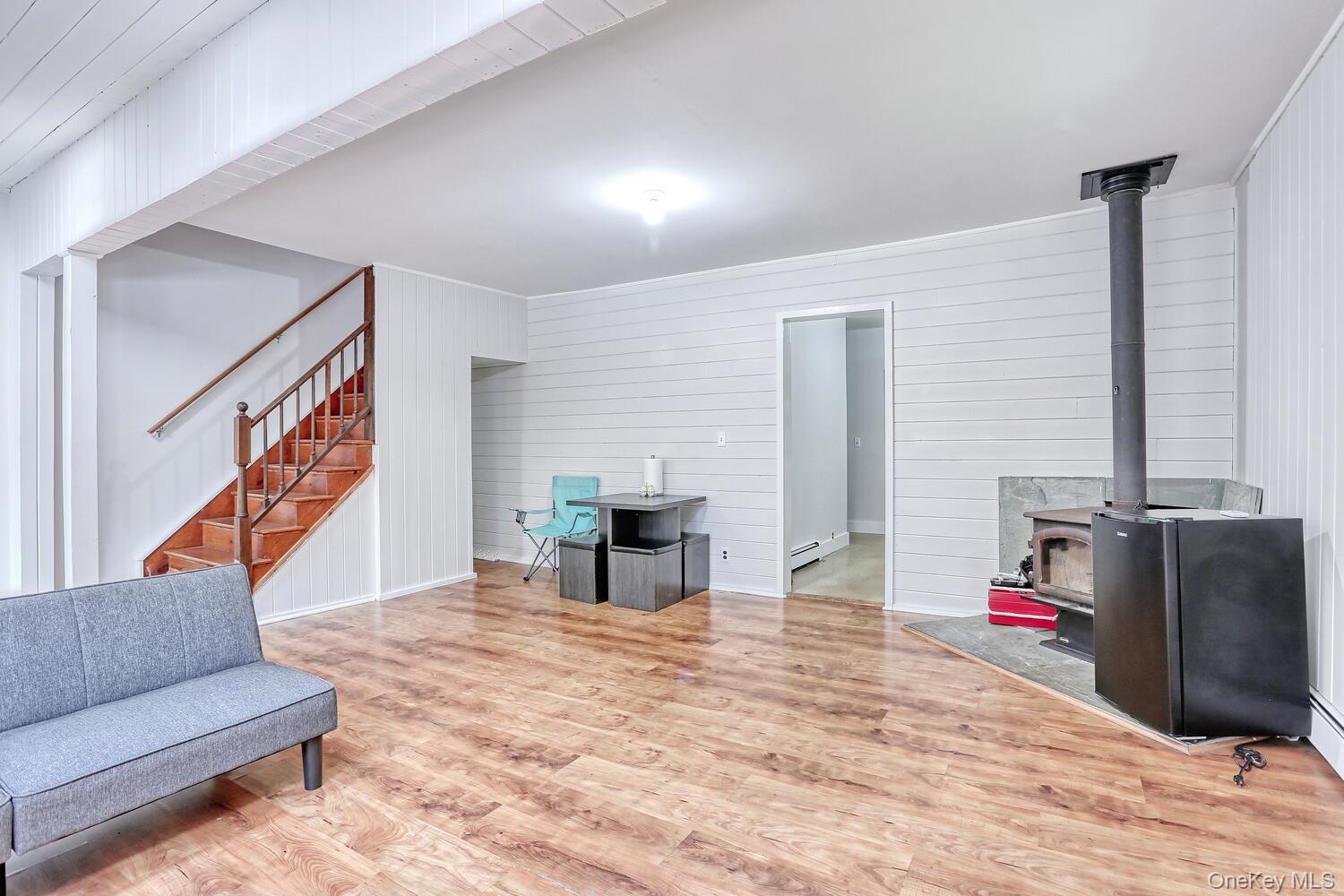 329 Call Hollow Road Haverstraw, NY 10980 - Photo 5 of 28 Living area with stairway, wood finished floors, a wood stove, and wooden walls
