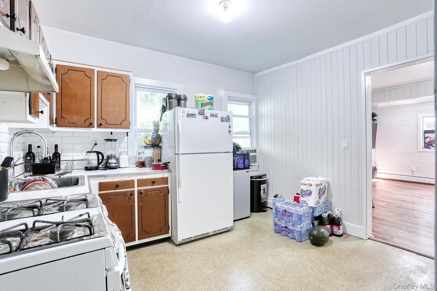 329 Call Hollow Road Haverstraw, NY 10980 - Photo 7 of 28 Kitchen with white appliances, light floors, light countertops, brown cabinetry, and wooden walls