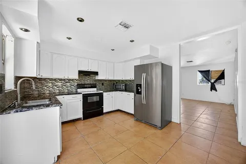a kitchen with granite countertop a refrigerator and a stove top oven