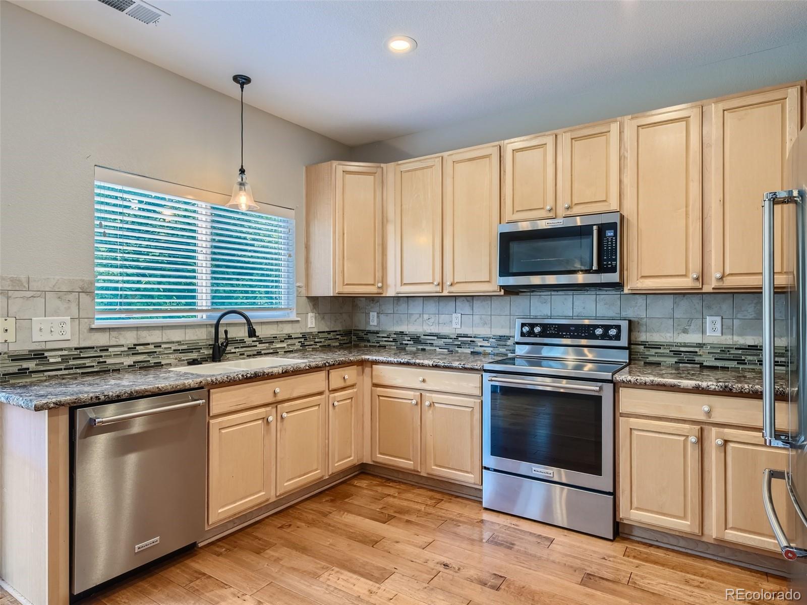 10574 Tracewood Circle Highlands Ranch, CO 80130 - Photo 5 of 21 a kitchen with stainless steel appliances granite countertop a stove a sink and a microwave