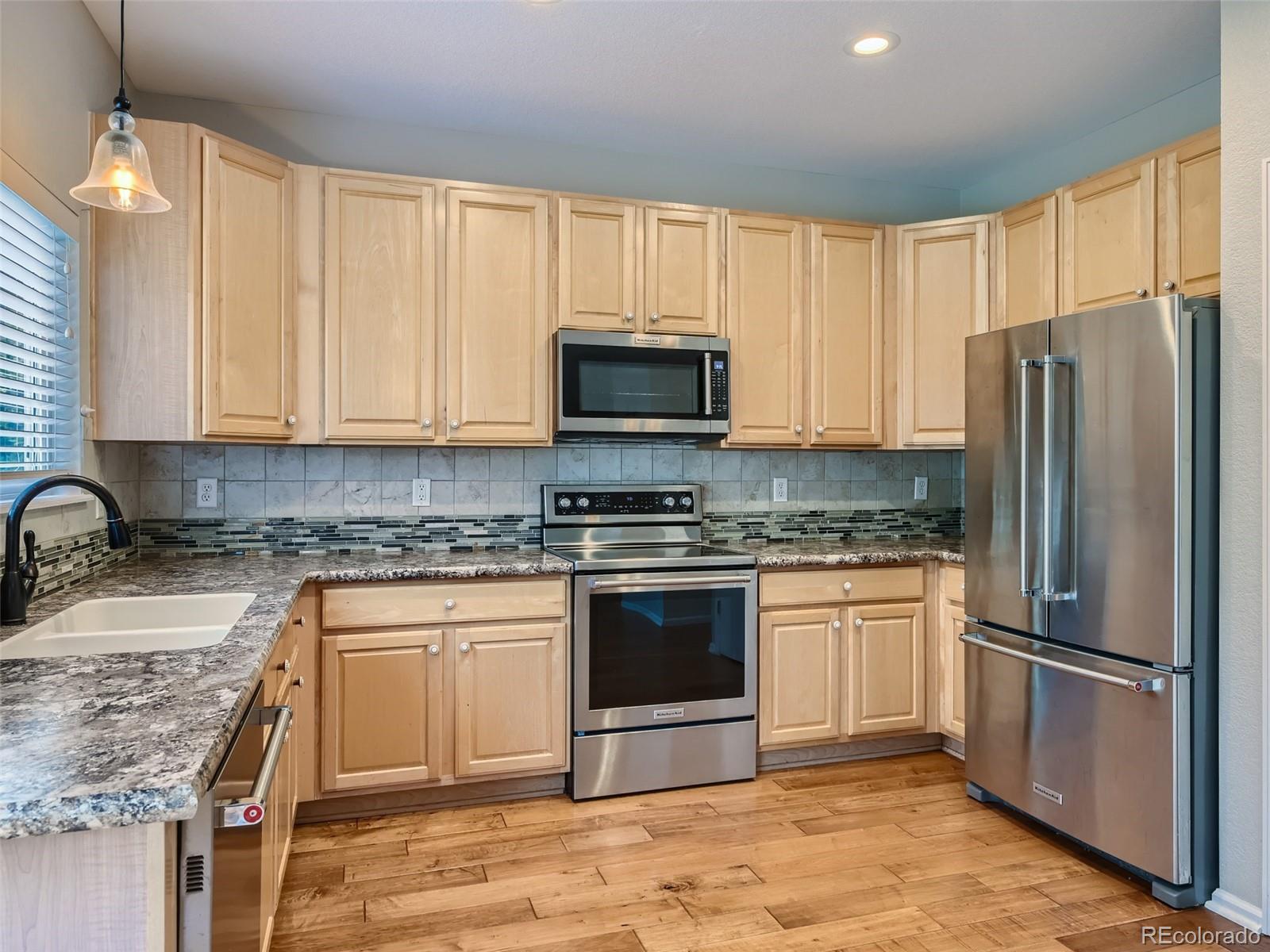 10574 Tracewood Circle Highlands Ranch, CO 80130 - Photo 6 of 21 a kitchen with granite countertop a stove top oven a sink and a microwave