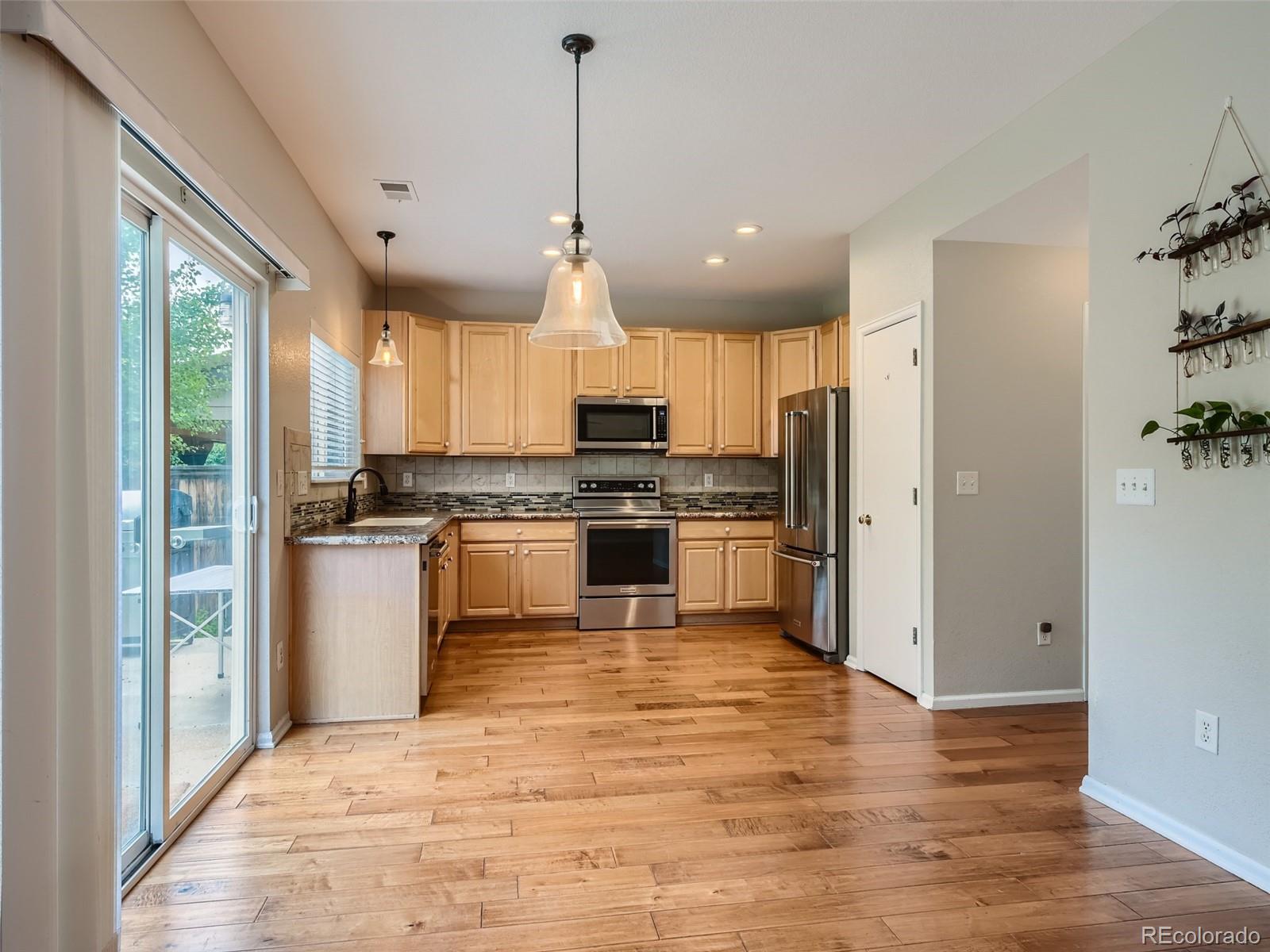 10574 Tracewood Circle Highlands Ranch, CO 80130 - Photo 7 of 21 a kitchen with granite countertop a refrigerator and wooden floor