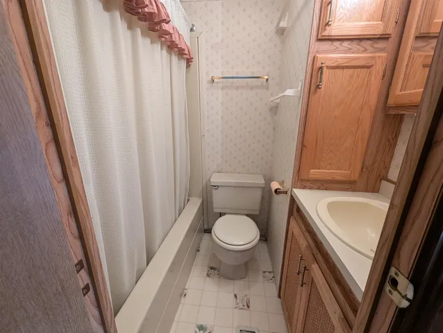 a bathroom with a sink a toilet a tub and shower
