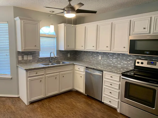 a kitchen with granite countertop cabinets stainless steel appliances and a window