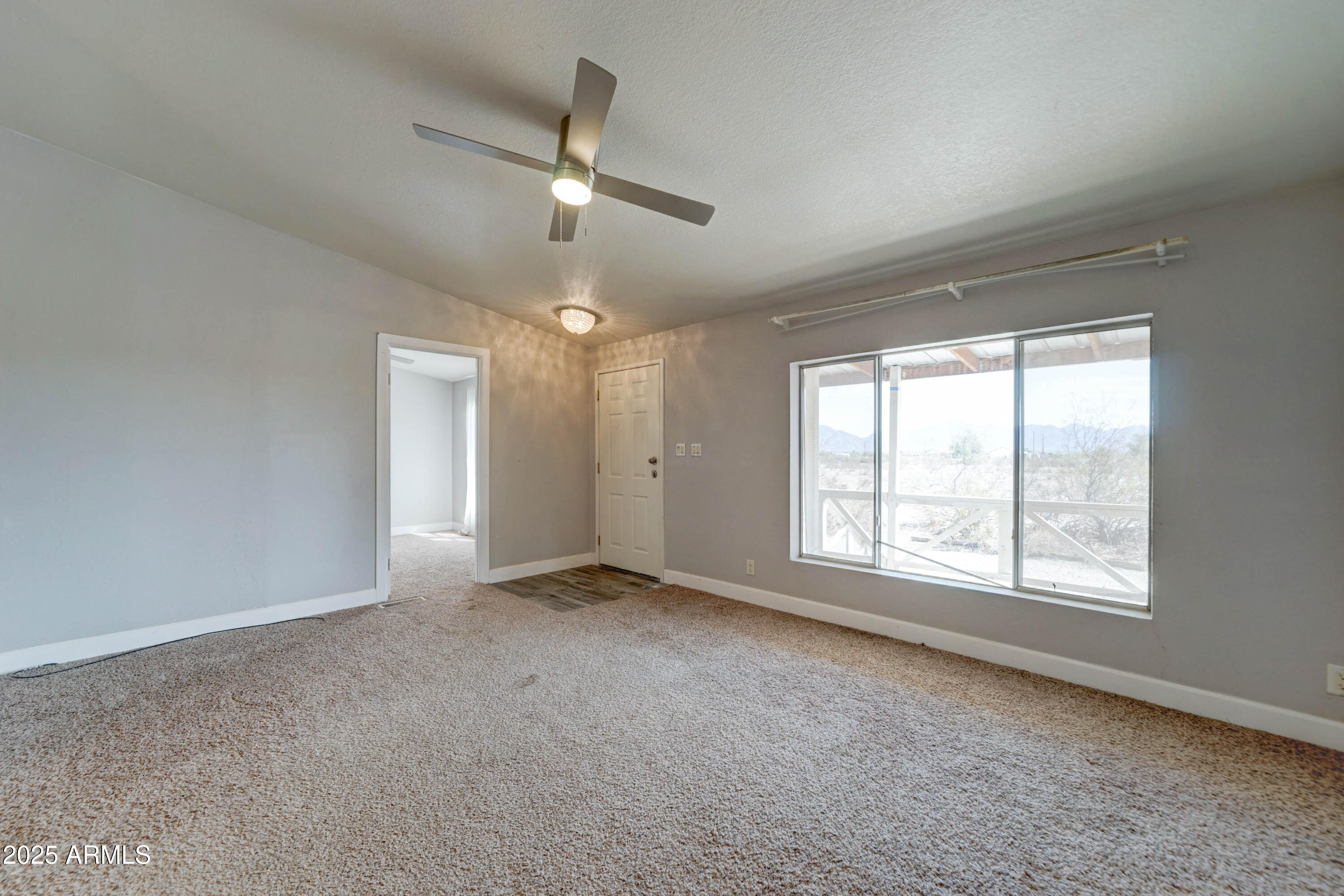 23402 South Manzanilla Road Buckeye, AZ 85326 - Photo 6 of 46 an empty room with chandelier fan and windows