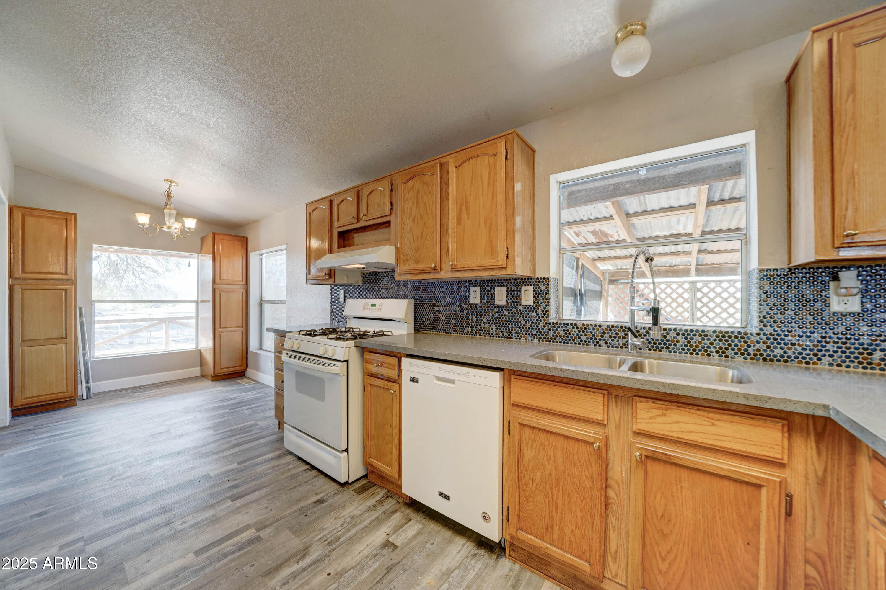 23402 South Manzanilla Road Buckeye, AZ 85326 - Photo 9 of 46 a kitchen with stainless steel appliances granite countertop a refrigerator a sink dishwasher a stove and white countertops with wooden floor
