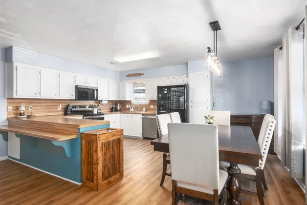 a kitchen with stainless steel appliances granite countertop a stove top oven a sink dishwasher and a refrigerator with wooden floor